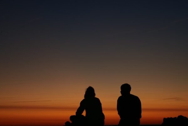 a couple of people sitting on top of a hill